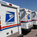 SCOTUS Votes 5-4, USPS Outcome Announced! Row of USPS mail delivery trucks parked.