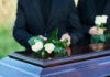 Iconic ’80s STAR DIES After Secret Cancer Fight People placing white roses on a casket.