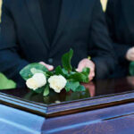 Documentary Star Found DEAD, Aged 25 People placing white roses on a casket.