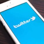 Close-up of a smartphone displaying the Twitter logo on a blue background