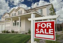 A suburban house with a For Sale sign in the front yard