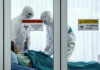 Ebola SURGE – Numbers Don’t Add Up! Healthcare workers in protective gear in quarantine room.