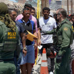 You Won’t Believe What They Are Giving Illegals For Free Now! Border patrol agents inspecting group of individuals in line.