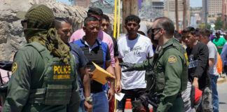 Border patrol agents inspecting group of individuals in line.