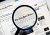 Magnifying glass over The New York Times website.