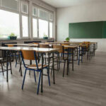 SICKO Teacher Forces Boy To Urinate In Class Empty classroom with desks, chairs, windows, and chalkboard.