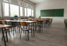 SICKO Teacher Forces Boy To Urinate In Class Empty classroom with desks, chairs, windows, and chalkboard.