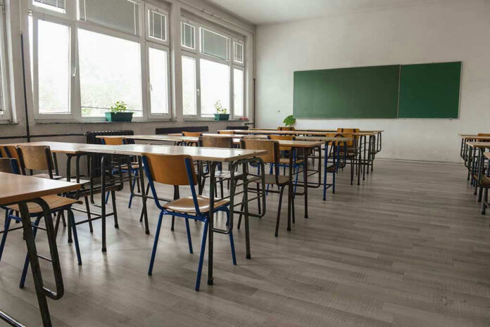 487861393 Empty classroom with desks, chairs, windows, and chalkboard.
