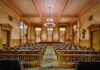 Courtroom Birth SHOCKER: Pregnant Woman Chained Interior view of a historic courtroom with wooden furnishings and chandeliers