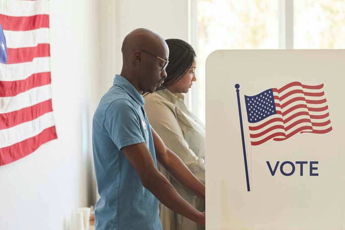 1810359025 People voting at polling booths with American flag.