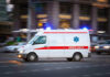 Paramedics On The Hook For Brutal Murder Ambulance driving on urban street with lights flashing.