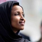 Woman wearing a black hijab looking thoughtfully into the distance