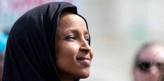 Woman wearing a black hijab looking thoughtfully into the distance