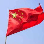 China Takes U.S Citizen HOSTAGE! Chinese flag waving against a clear blue sky