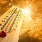 Air-Conditioning War BREAKS OUT Amid Deadly Heatwave! A thermometer displaying temperature against a sunset sky