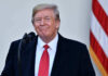 Trump Drops NATO Bombshell Immediately After Landing Man in suit and tie speaking at podium.