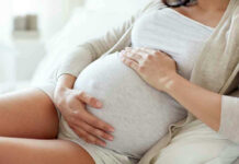 ALL Pregnant Travelers Need THIS For U.S Entry! Pregnant woman holding her belly, sitting comfortably.