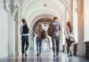 College Campuses STOCKPILING AR’s and Grenades – Why? Four students walking in a corridor together.