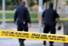 Student Snared in Bomb Plot After Terrifying Message Discovered! Police officers walking past caution tape at a crime scene