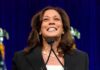 Kamala’s New Mansion Sparks Hypocrisy Uproar smiling woman speaking at a podium
