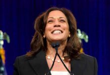Kamala’s New Mansion Sparks Hypocrisy Uproar smiling woman speaking at a podium