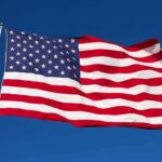 Rising Dem Star TRASHES U.S Flag During Campaign Rally Waving American flag against a clear blue sky