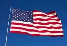 Rising Dem Star TRASHES U.S Flag During Campaign Rally Waving American flag against a clear blue sky