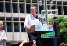 ICE Raids Newsom Press Conference Man speaking at a rally podium outdoors