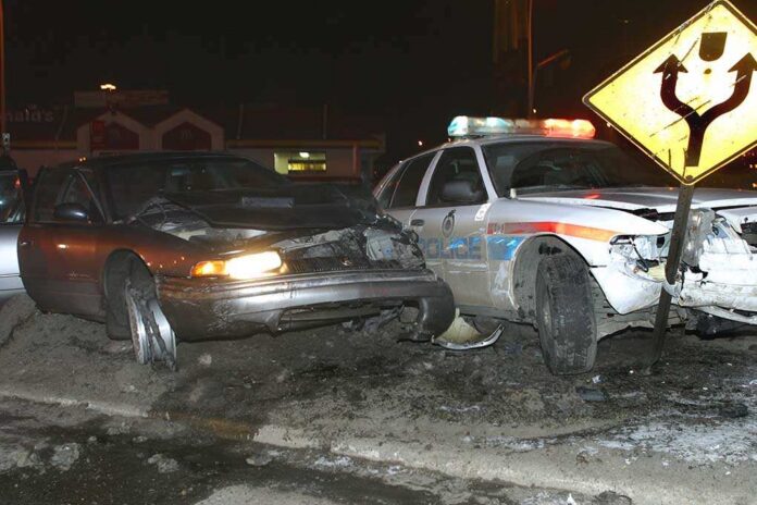 A,Crashed,Police,Cruiser,And,Chase,Car. A damaged car and a police vehicle involved in a nighttime accident