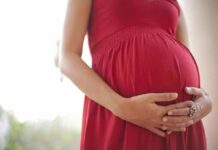 Pregnant woman in a red dress holding her belly