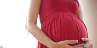 Pregnant woman in a red dress holding her belly