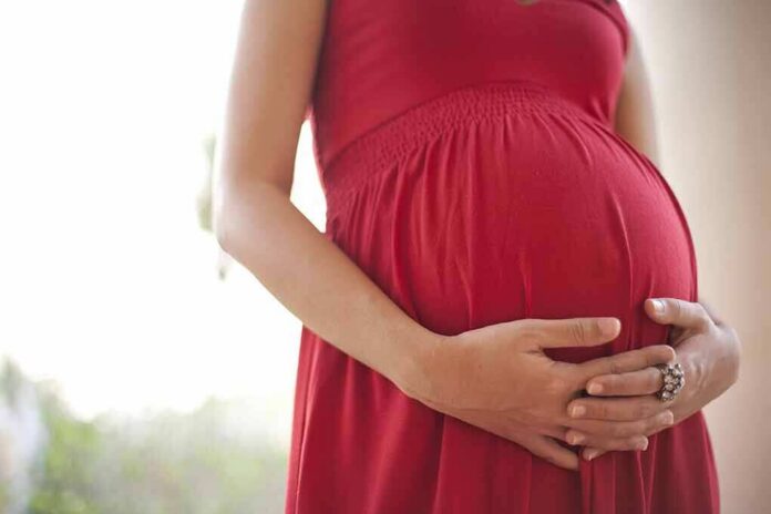 shutterstock_111643082 Pregnant woman in a red dress holding her belly