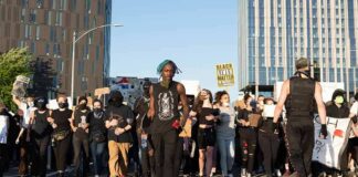 Protesters march down a city street holding signs