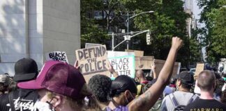 crowd at a protest holding signs and raising fists