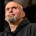 bald man with goatee speaking at a microphone