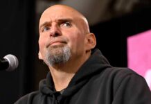 bald man with goatee speaking at a microphone
