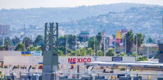 Border crossing booths at Mexico entry point with cityscape in background