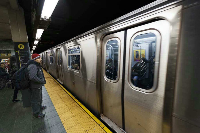 Subway train at platform with passengers inside and man waiting