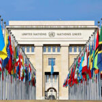 Netanyahu Torches Mamdani During Speech United Nations building with numerous national flags outside.