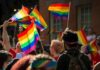 162 LQBTQ ARRESTED in Midnight Raid Crowd waving rainbow flags at an outdoor event