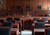 Maniac Storms Into Courthouse With Loaded Gun! Empty courtroom with wooden benches and judge's bench