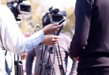 press interview with microphones and cameras outdoors