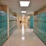 Illegal Migrant Charged With Murder of NCAA Football Player School hallway with rows of teal lockers