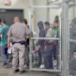 Dem Candidate Would Trade Five Americans for One Illegal Detention facility with people behind chain-link fence and officer nearby