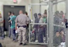 Dem Candidate Would Trade Five Americans for One Illegal Detention facility with people behind chain-link fence and officer nearby
