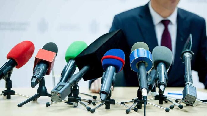 shutterstock_1245040021 microphones clustered on a table at a press conference