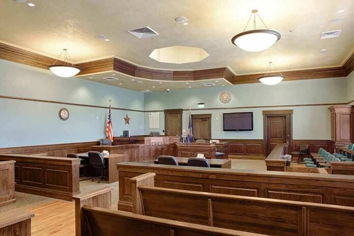 shutterstock_1349439551-2 Empty courtroom with wooden benches and judge's bench