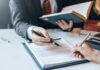 Hands signing a legal document at a desk