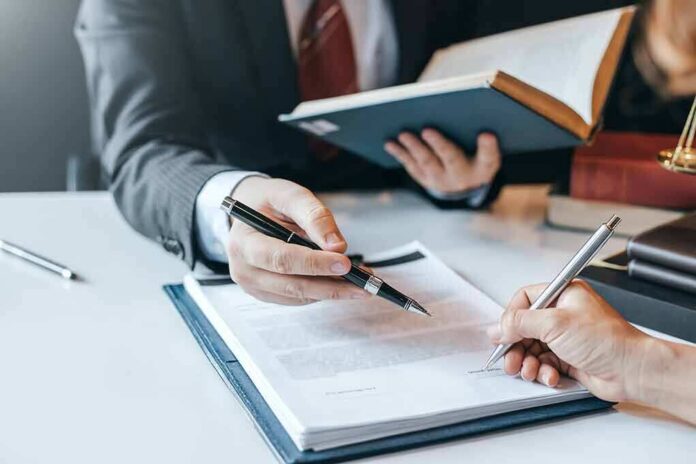 shutterstock_1414855505 Hands signing a legal document at a desk