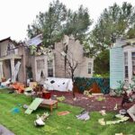 Houses with significant storm damage and debris scattered around the yard